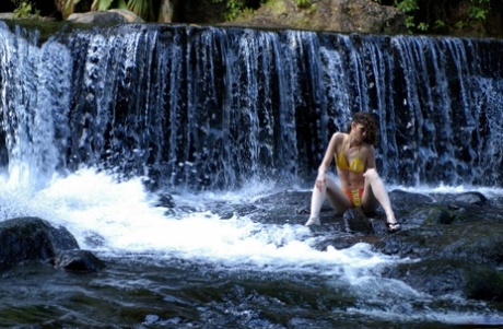 A rapariga solitária Liana despe os seus calções de banho para ficar nua em frente a uma cascata