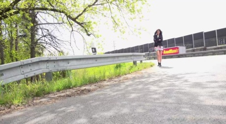 Ali Bordeaux pisse sur le bord de la route pendant que des camions passent.