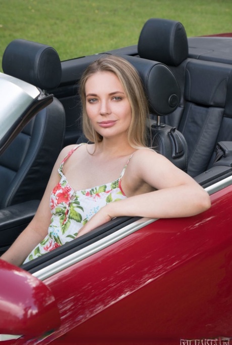 Den unge blonde Maxine er nøgen i en indkørsel ved siden af en cabriolet.