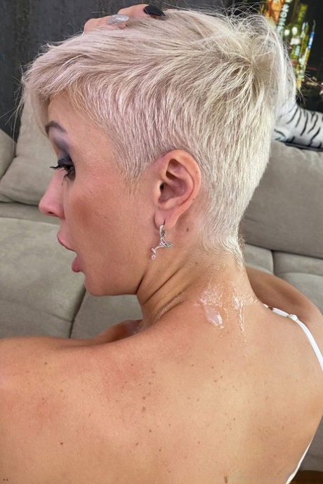 La blonde platine tatouée Tanya Virago tient une bite après avoir montré sa chatte percée.