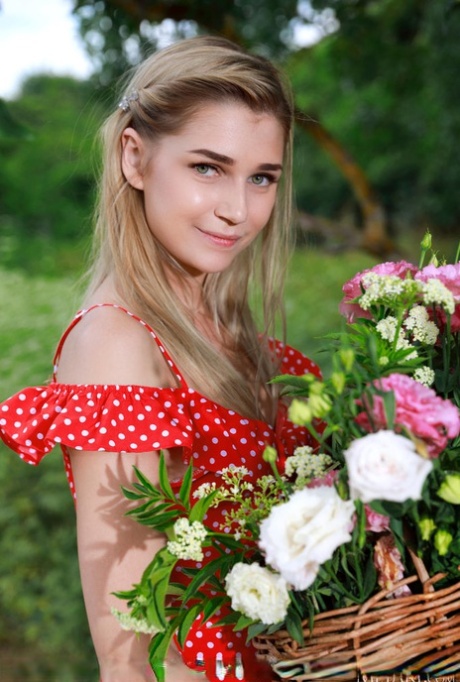 Jovem loira Christine Cardo fica nua num campo montanhoso enquanto colhe flores