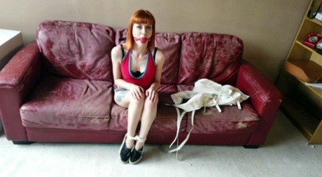 Kinky redhead affixes herself with a ball gag before tying herself up