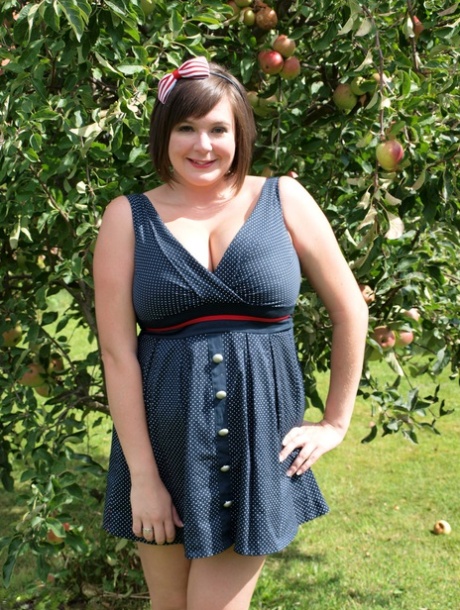 La grosse amatrice Roxy montre ses jambes nues dans une robe courte dans le jardin.