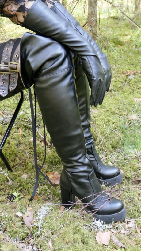 Bekleidete Frau mit Lederhandschuhen und Stiefeln sowie Sonnenbrille im Wald
