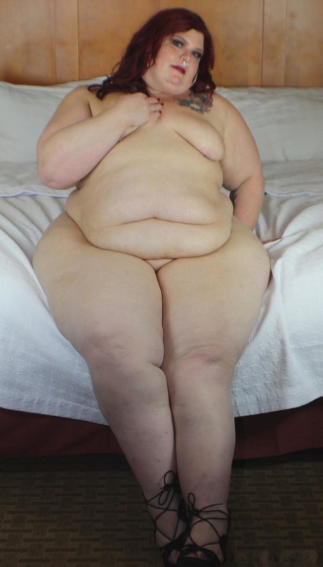 Roodharige SSBBW Nikki Cakes toont haar enorme kont terwijl ze met haar gezicht naar beneden op een bed ligt