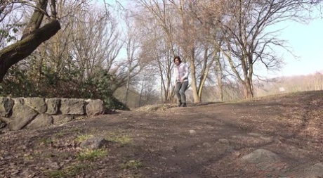 Caucasian girl Lara Fox pee atop a stone retaining wall in the country