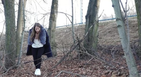 Kurzes genommenes Mädchen zieht Strumpfhosen herunter, um zu pinkeln, während sie durch den Wald geht