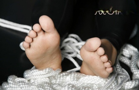 Biała kobieta prezentuje swoje piękne stopy z pomalowanymi na czarno i czerwono paznokciami.