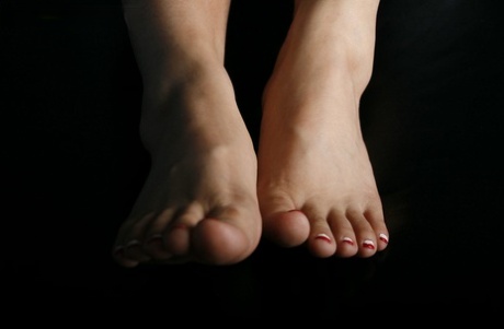 Mujer caucásica desconocida muestra las uñas de los pies y las plantas de los pies pintadas