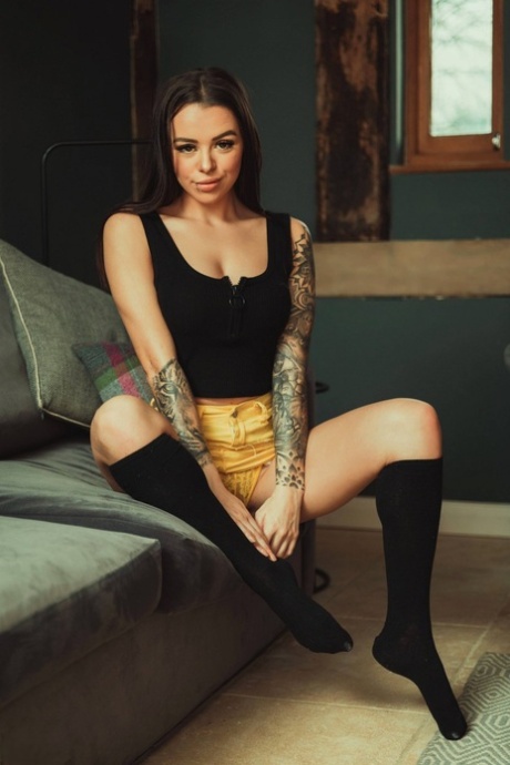 Den tatoverte modellen Mia Stryker tar av seg de fine puppene iført svarte knestrømper.