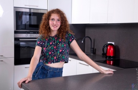 Teen solo girl Foxy Lee sports curly red hair while getting naked in a kitchen