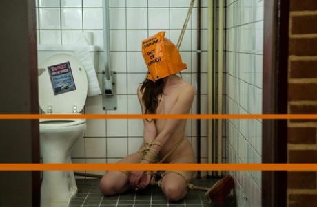 La femmina caucasica è legata in un bagno con una borsa in testa
