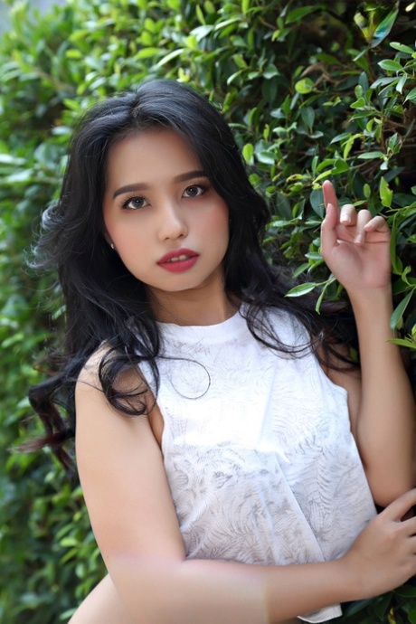 Schöne asiatische Mädchen Norah wird völlig nackt neben einer Hecke in einem Garten