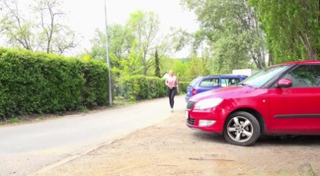 Blondes Mädchen Emily Bright zieht Leggings neben einem Auto herunter, um dringend pinkeln zu müssen