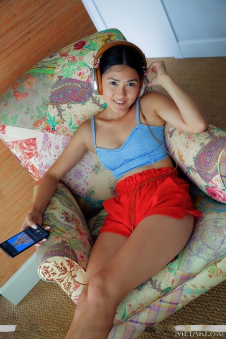 Junges asiatisches Mädchen Kimiko wird nackt in Socken mit Tiermuster auf einem Stuhl