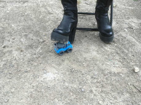 Onbekende vrouw steekt een dinky toy in de grond met zwarte leren laarzen