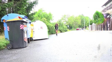 La chica de baja estatura Ali Bordeaux se pone en cuclillas para orinar en una carretera junto a los contenedores de basura