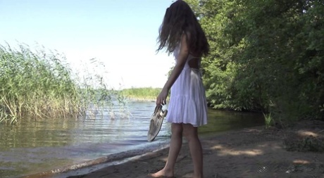 Caucasian girl Sasha wades into shallow water before taking a piss