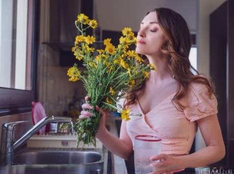 A simpática adolescente Julietta fareja flores cortadas frescas antes de ficar nua na sua cozinha.