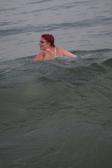 Pelirroja tatuada posa desnuda en una playa antes de masturbarse en la tapa de un váter