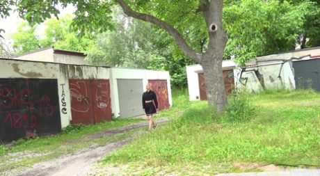 Blondes Mädchen Nykla zieht ihr Kleid hoch, bevor sie in einer Garage pisst