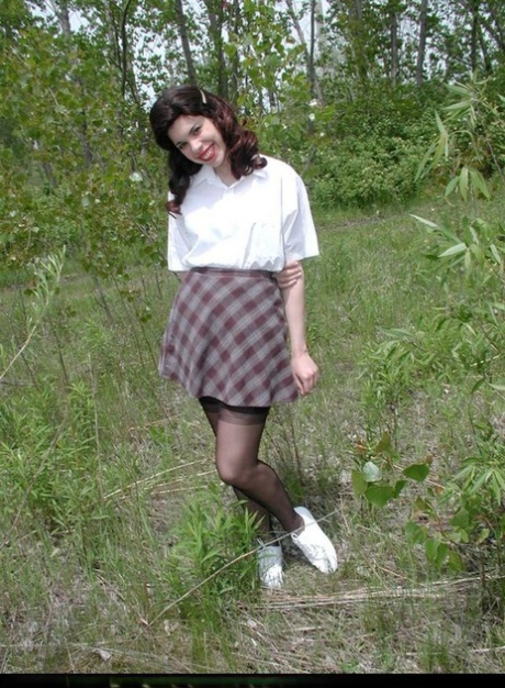 Amateur girl doffs retro clothes while wearing nylons in a field