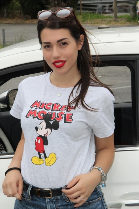 Heet meisje toont haar sexy voeten in een auto terwijl ze een Mickey Mouse T-shirt draagt