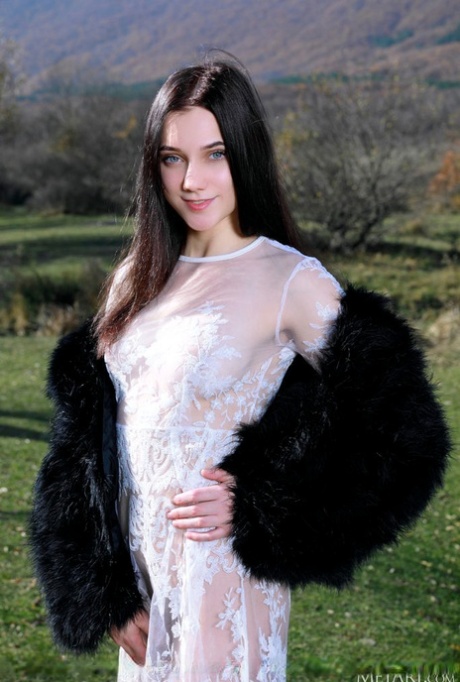 La jolie adolescente Polly Pure enlève une robe en dentelle blanche pour poser nue dans une cour de campagne.