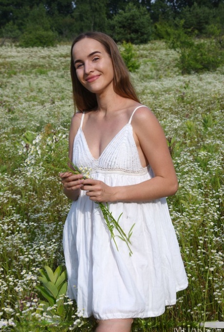 Eva Jolie kleedt zich charmant uit in het midden van het bloemenveld en toont