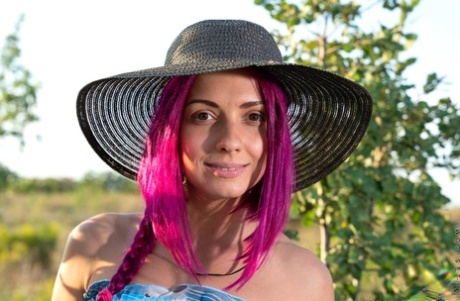 La modella amatoriale Victoria Rainbow si spoglia su un muro di contenimento con un cappello da sole