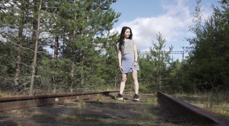 Donkerharig meisje Alyona neemt een plas terwijl ze langs het spoor loopt