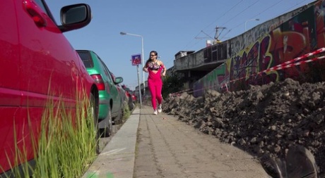 A menina branca Barbara Bieber puxa para baixo as leggings cor-de-rosa para mijar numa calçada