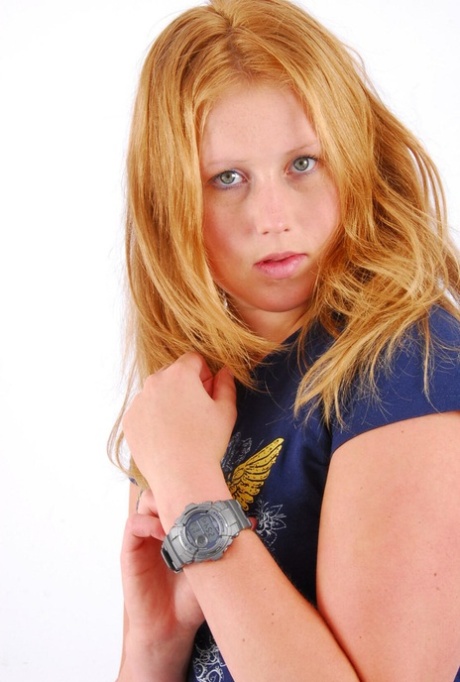 Rudowłosa Judy prezentuje swój szary zegarek G-Shock w koszulce i dżinsach.