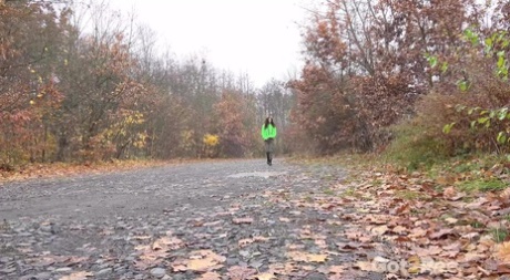 Ali Bordeaux pisse sur un chemin de gravier en portant des bottes noires.