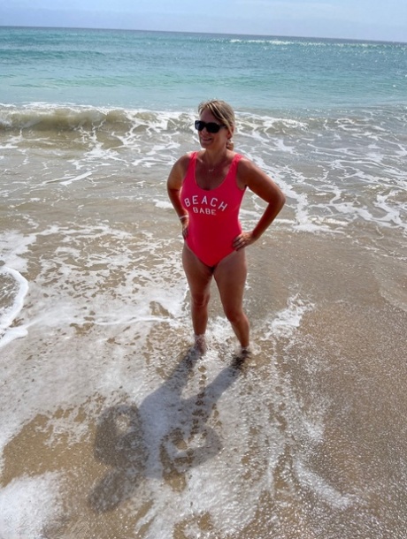 Den middelaldrende blondinen Sweet Susi kler seg helt naken på en sandstrand.