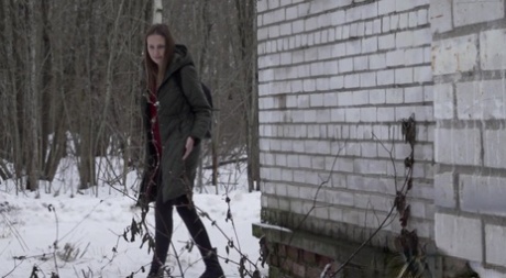 Blank meisje Valya gaat pissen naast een gebouw in de winter