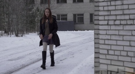 La ragazza caucasica Valya piscia nella neve dopo essersi nascosta dietro un edificio