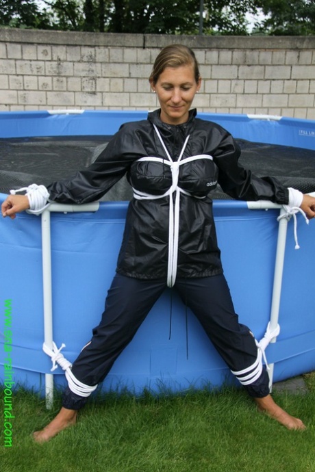 Sandra, une femme amateur, est bâillonnée et attachée à une piscine dans un imperméable.