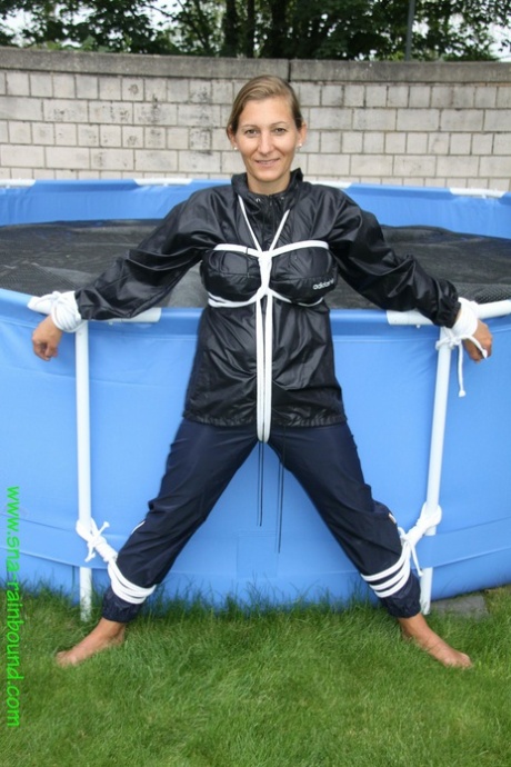 Sandra, une femme amateur, est bâillonnée et attachée à une piscine dans un imperméable.