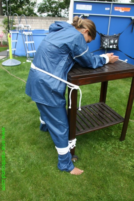 Caucasian woman is tied to a table in a yard with panties over her face