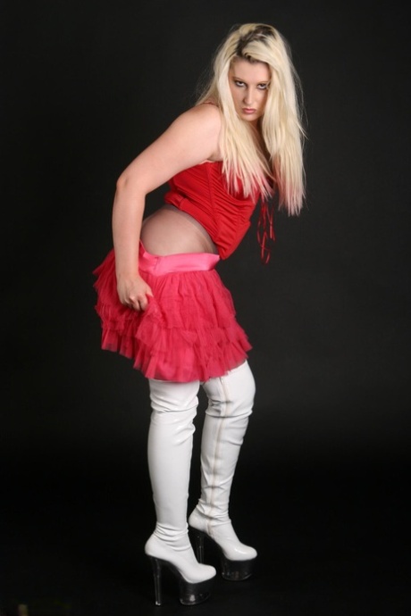 Blond, kvinnelig Avengelique tar av seg skjørtet mens hun har på seg rene strømpebukser.