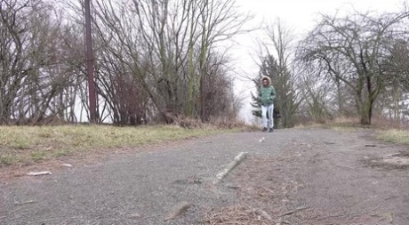 Ali Bordeaux takes a pee beside a walking path while wearing a winter coat