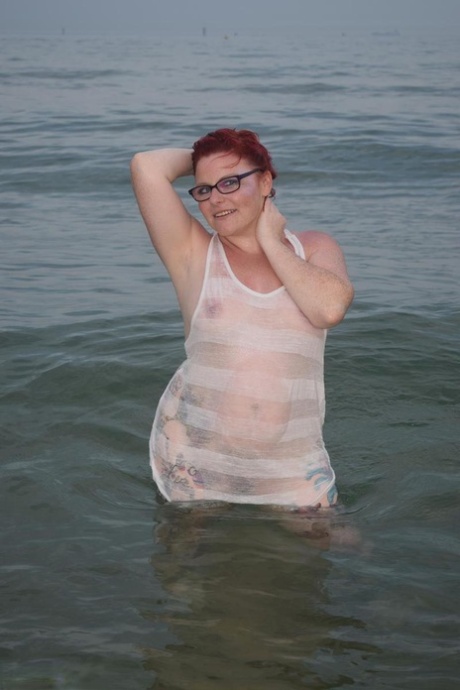 A ruiva madura Mollie Foxxx molha o seu corpo tatuado no oceano