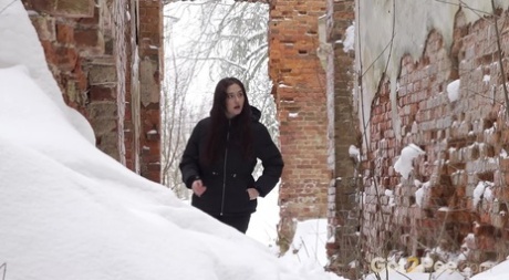 A rapariga branca Alexa baixa as calças para urinar urgentemente no chão coberto de neve