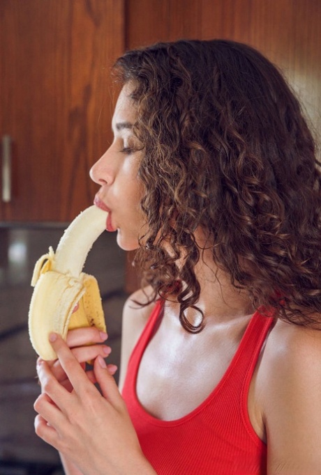 Jong meisje met golvend brunette haar Cristin gaat naakt na het eten van een banaan