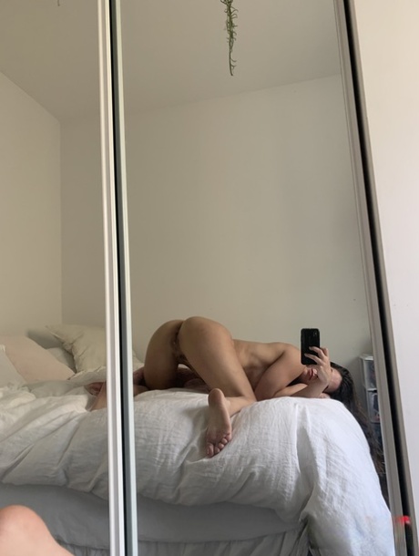 Brunette amateur neemt selfies terwijl ze naakt voor de spiegel staat