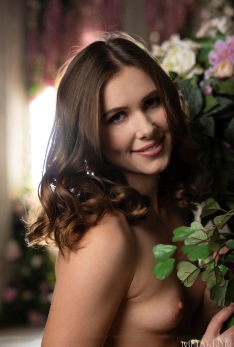 Den vackra flickan Amber Pearl hittar på fantastiska nakenposer nära blommor