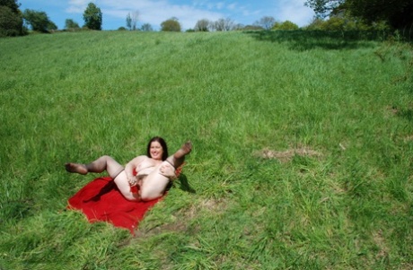 Brittisk amatör Juicey Janey dildos hennes buske på en röd filt på ett fält