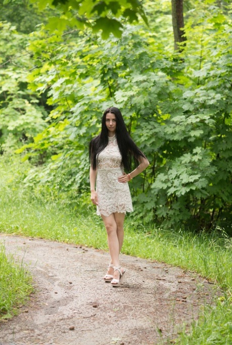 Młoda dziewczyna z długimi czarnymi włosami Veronica Snezna nago w szpilkach w parku