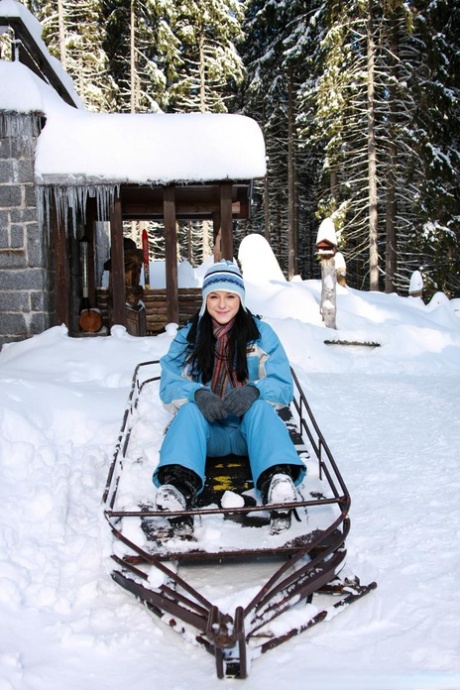 Une jeune brune baisse son pantalon de neige pour se masturber dehors dans la neige.